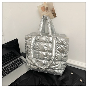 Detailed macro view of silver metallic quilted tote bag with wide strap and zipper closure
