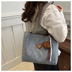 Détail du sac cabas gris avec bandoulière en cuir, chaîne et pendentif ours mignon
