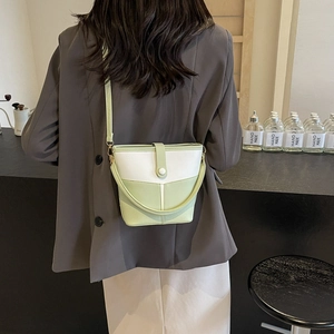 Detail of mint green and white color-block bucket bag with flap and long strap