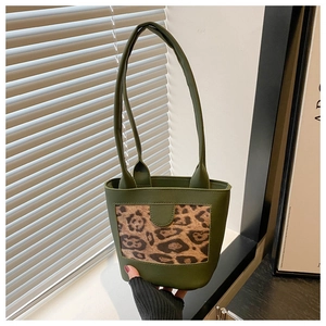 Detailed view of dark green bucket bag featuring leopard print leather panel and straps