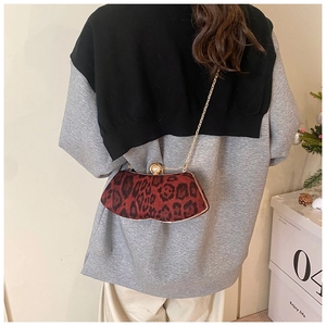 Détail de la pochette léopard rouge avec fermoir perle et fine chaîne dorée