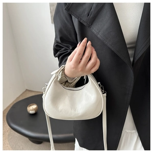 Detail of white crescent leather handbag with silver metallic zipper and shoulder strap