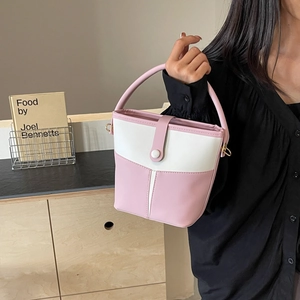 Detail view of contrast color bucket bag in pink and beige with smooth PU leather texture