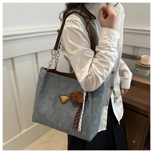 Détail du grand sac cabas en toile grise avec poignées en cuir marron et pendentif en ours