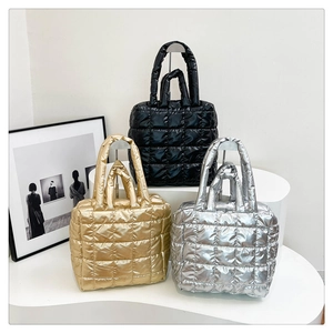 Close-up of quilted down tote bags in metallic black gold and silver on a white display stand