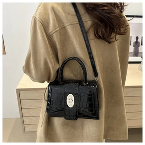 Détail du sac à main noir motif crocodile avec fermoir rotatif ovale en métal argenté