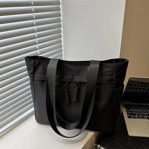 Minimalist black large capacity tote bag for women commuting placed on office desk