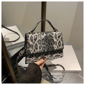 Détail du sac à main léopard montrant les ferrures dorées et la structure en accordéon