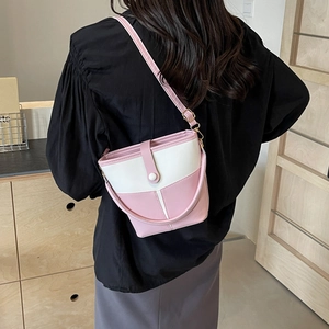 Detail view of pink and white bucket bag featuring leather patchwork and thin shoulder strap