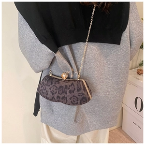 Détail du sac de soirée léopard avec cadre doré et fermoir perle porté à l'épaule