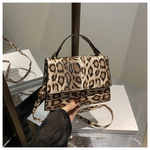 Détail du sac bandoulière léopard avec poignée en cuir noir et finitions métalliques