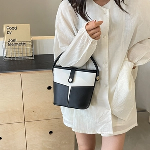 Model showcasing a contrast color bucket bag in black and white leather with a top handle