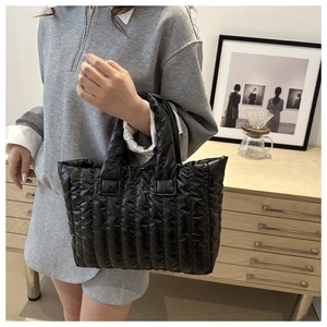 Détail d'un sac cabas matelassé noir brillant avec des poignées rembourrées et douces