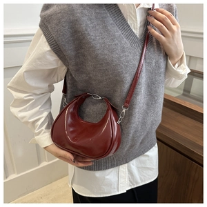 Detail of burgundy glossy patent leather crescent bag with silver metallic hook and strap