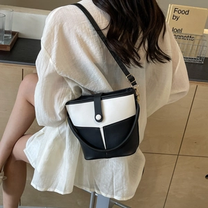 Detail view of black and white bucket bag styled with an oversized white shirt outfit