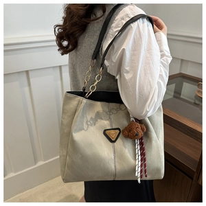Détail du grand sac cabas gris-vert avec chaîne dorée et breloque ours sur l'épaule