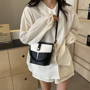 Detail view of the black and white bucket bag featuring matte PU leather and gold buckle