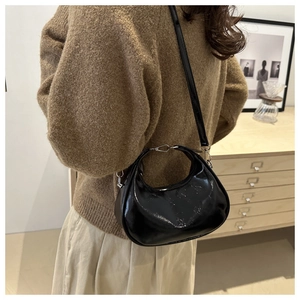 Stylishly glossy black faux leather hobo bag worn by model in a minimalist room