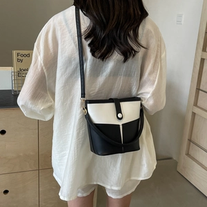 Detail of a minimalist black and white bucket bag with PU leather and metal hooks