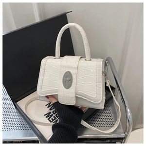 Détail de la texture croco blanche et du fermoir tournant ovale argenté sur le petit sac