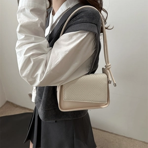 Minimalist beige crossbody bag with textured flap and elegant rope shoulder strap