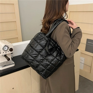 Chic black quilted puffer tote bag shown on model in a modern interior setting