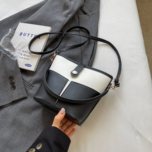 Detail view of contrast bucket bag with adjustable strap and metal magnetic closure