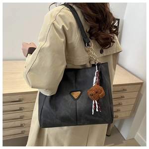 Détail du grand sac cabas noir mat avec logo doré et pendentif ours en peluche doux