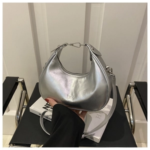 Detailed view of silver crescent bag with metallic finish and DX logo on white books