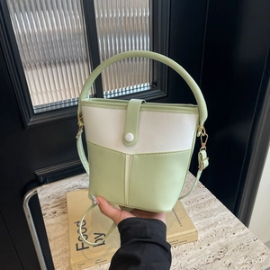 Detail of green and white color-blocking bucket bag with adjustable strap and handle