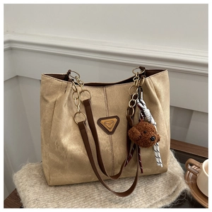 Détail du sac fourre-tout kaki avec texture toile, anse en cuir marron et chaîne dorée
