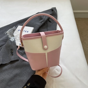 Close-up of pink and beige bucket bag with vertical textured stripes and handle