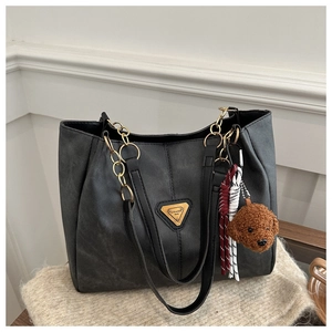 Détail du sac cabas en cuir noir avec chaîne dorée et charm d'ours en peluche