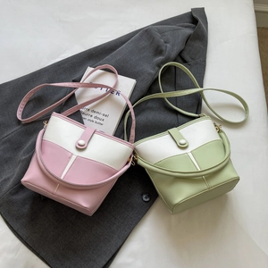 Close-up of stylish patchwork bucket bags in pink and green on a soft fabric background
