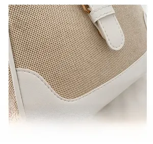 Detailed close-up of beige canvas texture with white leather trim and gold metal buckle