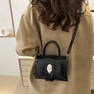 Sac à main noir à motif crocodile avec boucle en métal argenté sur fond de manteau en laine