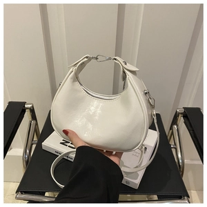 Detailed macro view of the glossy white crescent bag's leather texture and silver hardware