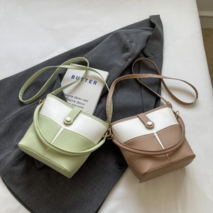 Detail view of two-tone bucket bags with top handle and magnetic closure on textured PU
