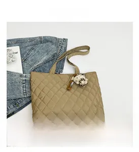 Detailed close-up of khaki quilted tote bag with a cute leopard-print plush doll charm