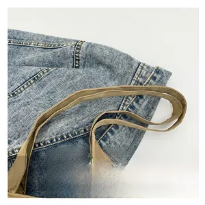 Detailed close-up of blue denim tote bag with durable khaki shoulder strap and stitching