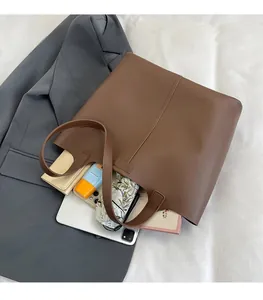 Brown faux leather bucket bag showing large capacity with tablet, umbrella and books