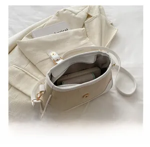 Detail view of the spacious inner compartment with phone storage in a woven beige crossbody bag