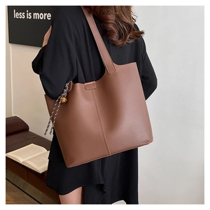 Detail of vintage brown tote bag with woven cord pendant and smooth leather texture
