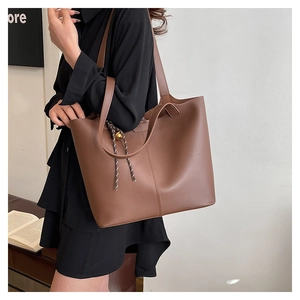 Close-up of brown PU leather tote bag with elegant drawstring and gold metal charm