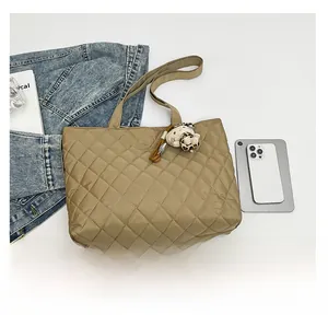 Close-up of khaki quilted tote bag with leopard print cat charm and shoulder straps