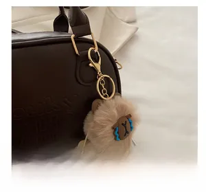 Vue détaillée du charm de sac Capybara en peluche avec fermoir doré sur un sac à main