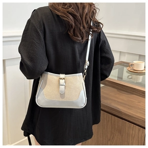 Detail of canvas bag with light blue faux leather trim and buckle on a wooden surface