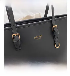 Dettaglio borsa tote in pelle nera a grana incrociata con logo e finiture dorate