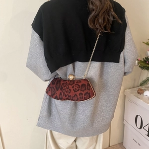 Sac à main vintage léopard bordeaux avec bordure dorée et fermoir perle porté par mannequin