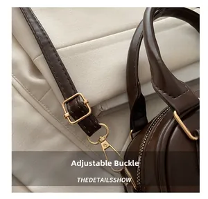 Gros plan sur la boucle en métal doré et les coutures du sac à main en cuir marron